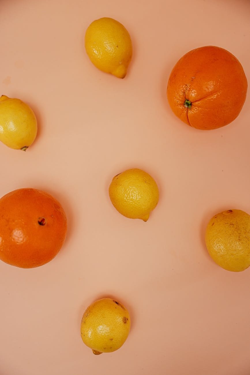 oranges and lemons on pink surface