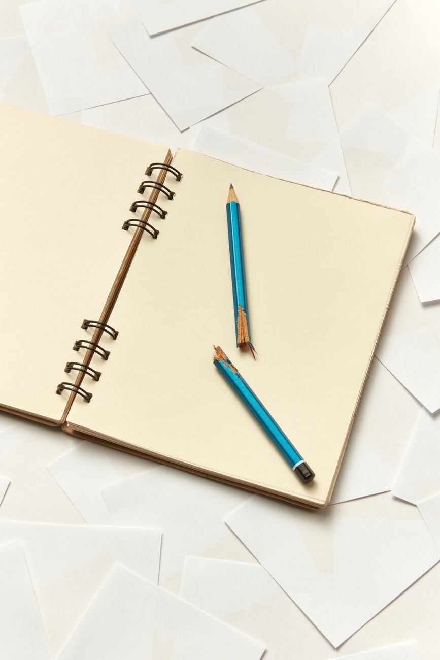 a notebook with a broken pencil on scattered white papers